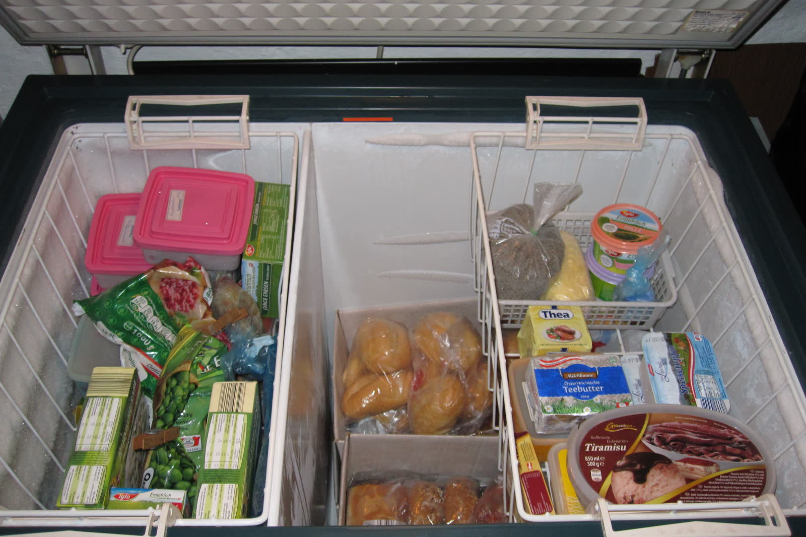 Open chest freezer with wire baskets full of frozen food