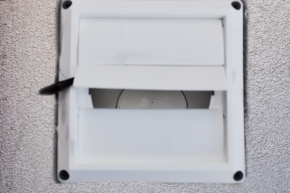 Louvered dryer vent hood on an outside wall with the damper flap open