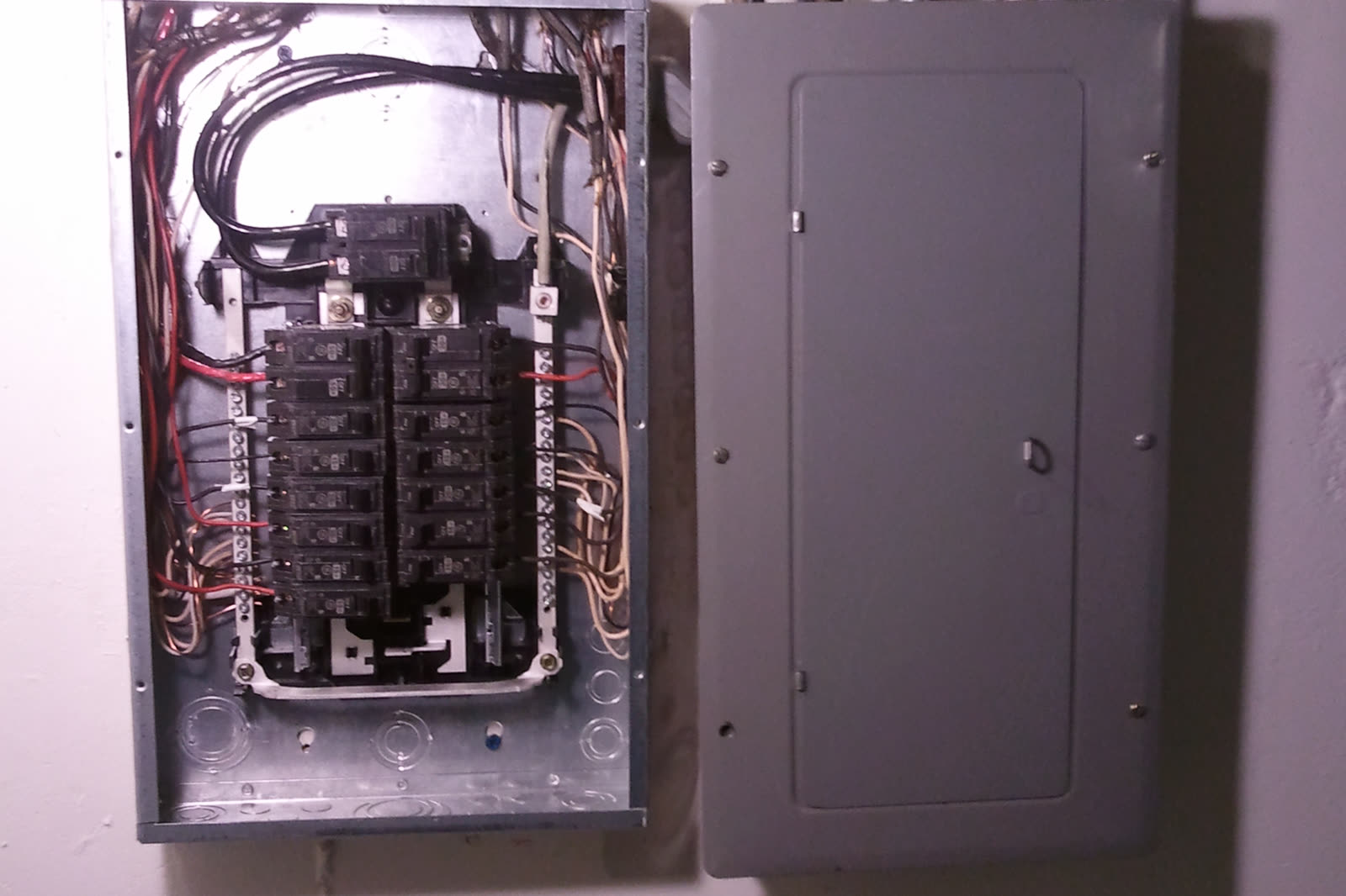 Main electrical panel beside a subpanel with its cover removed