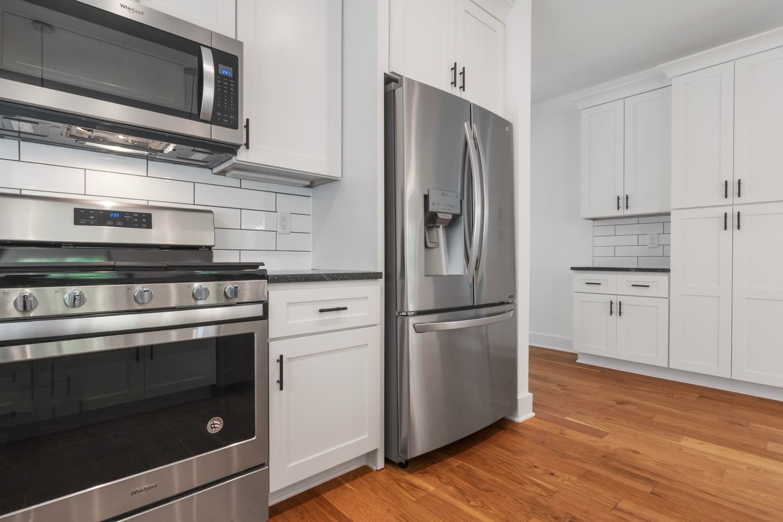 Stainless French-door refrigerator in a white kitchen next to a range
