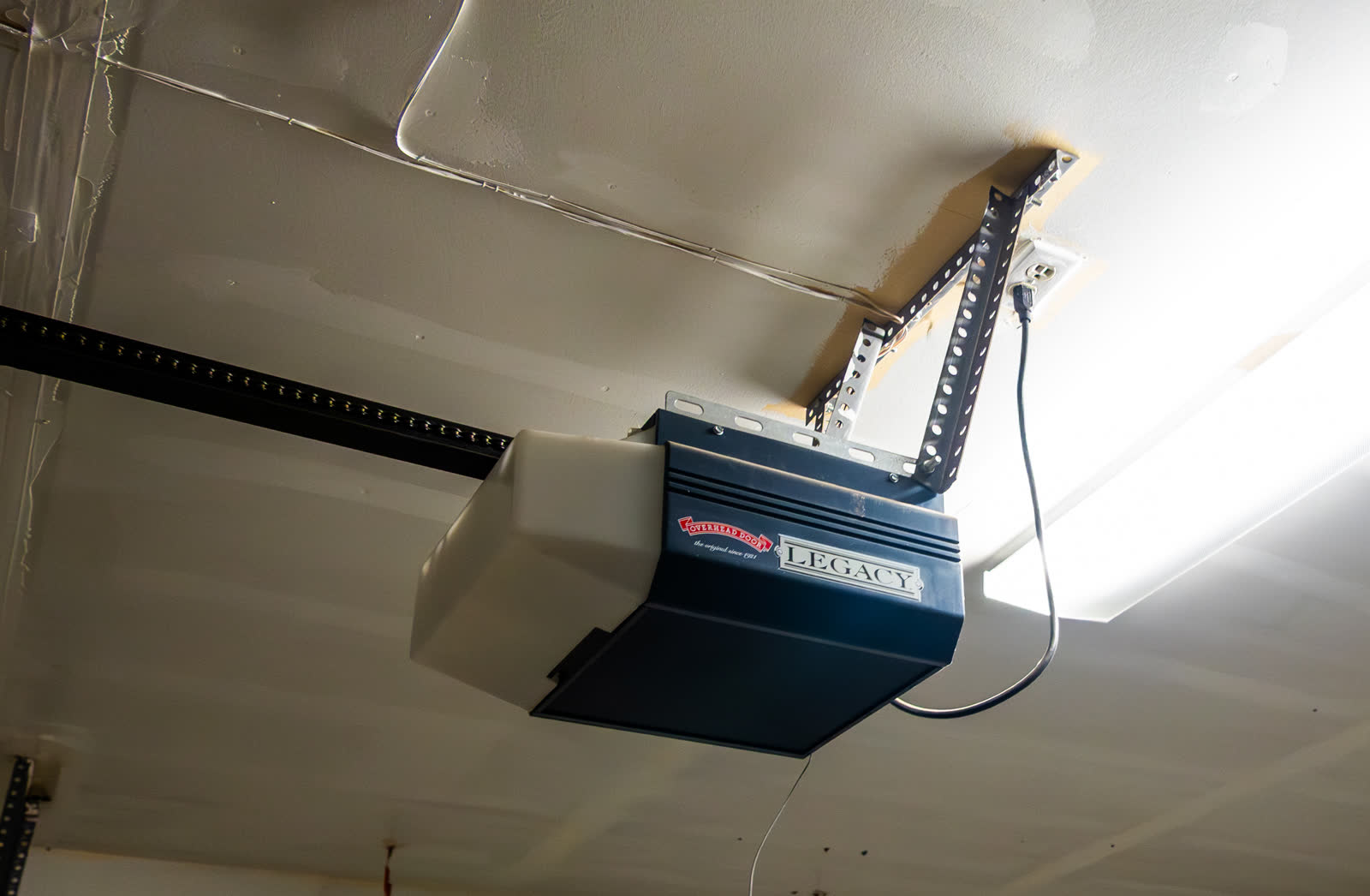 Ceiling-mounted garage door opener with its rail and power cord