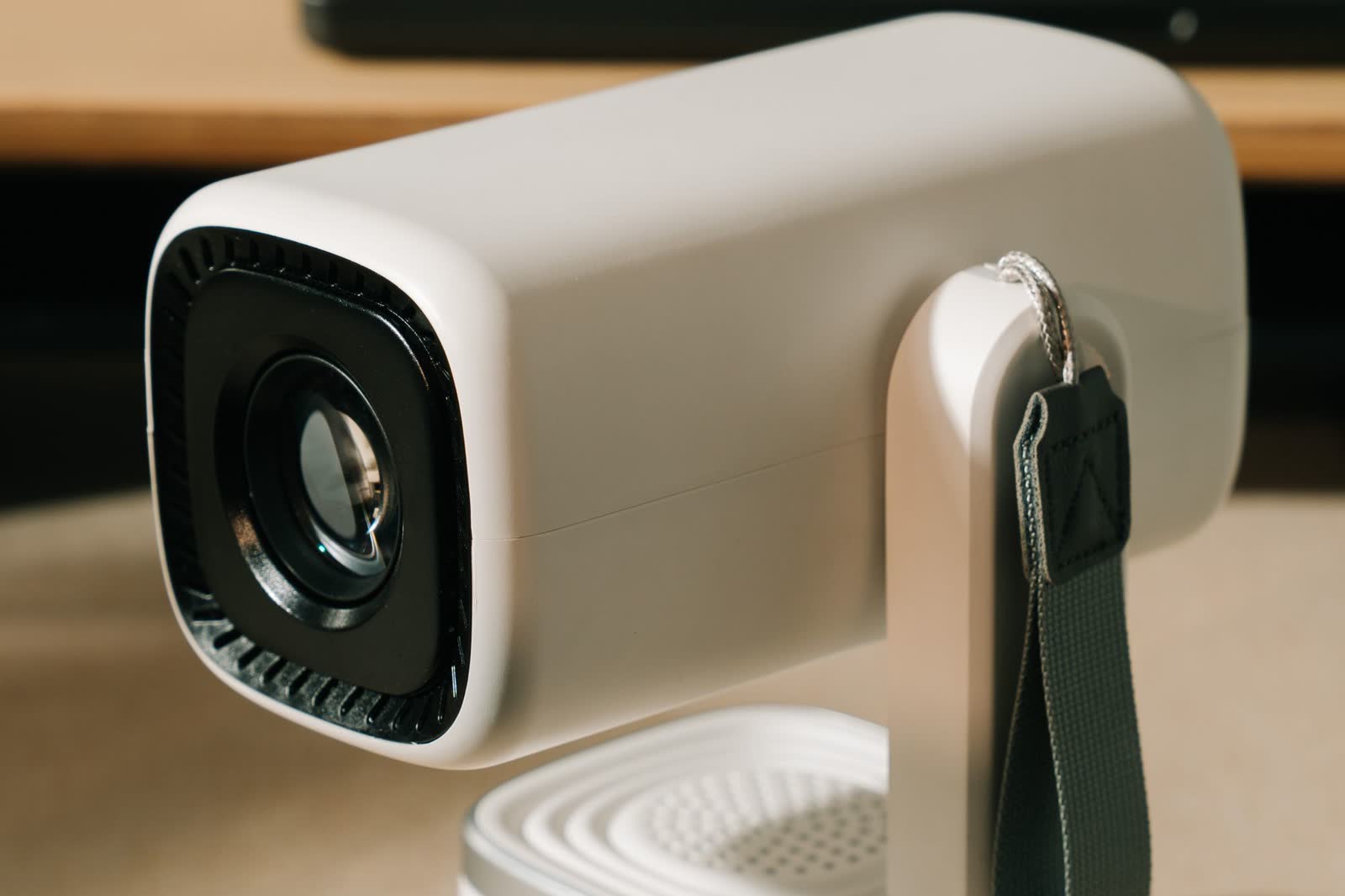 Compact white home projector seen from the lens side