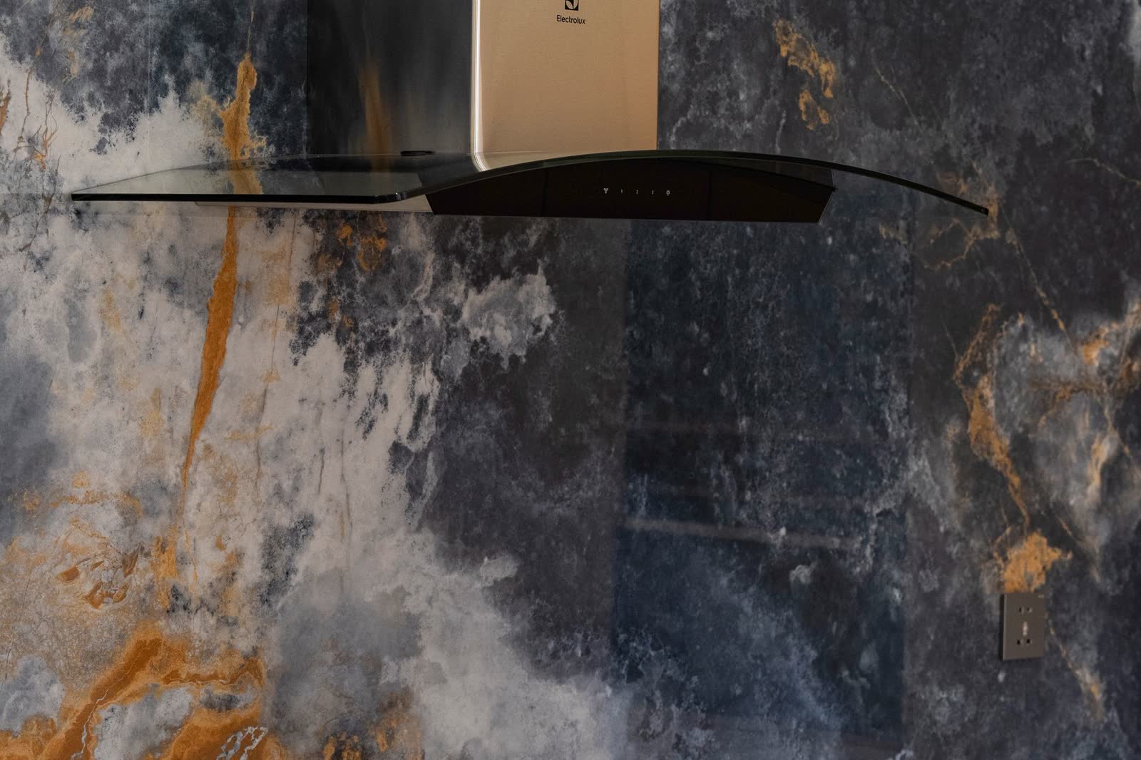 Chimney-style range hood with a glass canopy over a cooktop