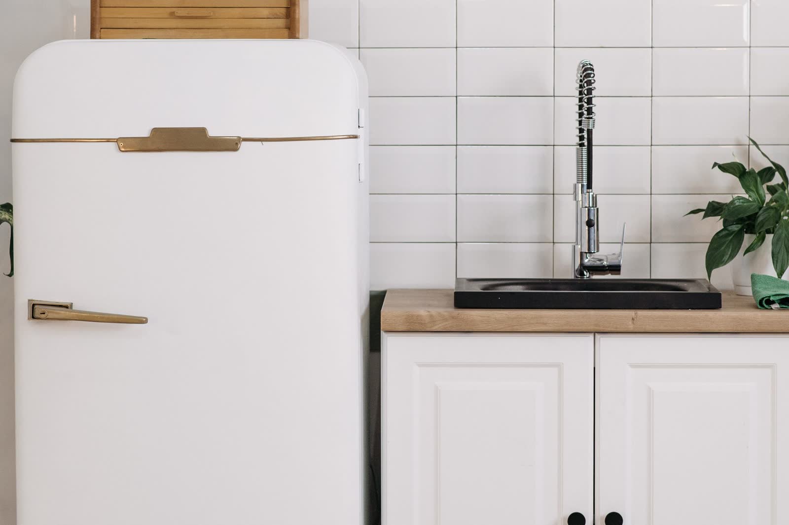 White retro-style refrigerator beside a kitchen sink cabinet