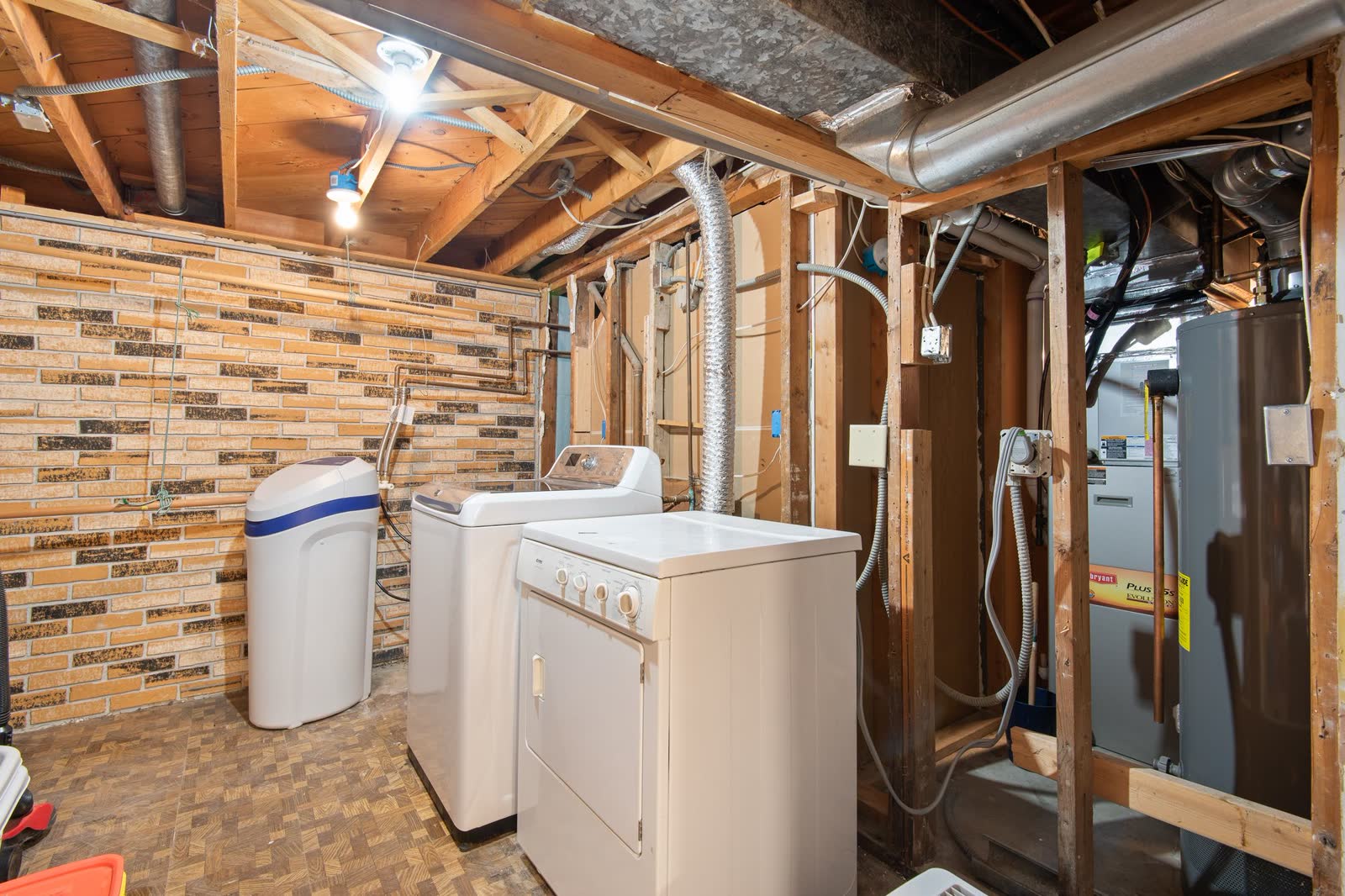 Basement laundry area with a top-load washer and dryer next to utility equipment