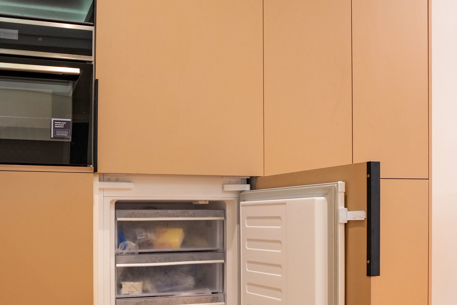 Integrated upright freezer with its door open showing drawers
