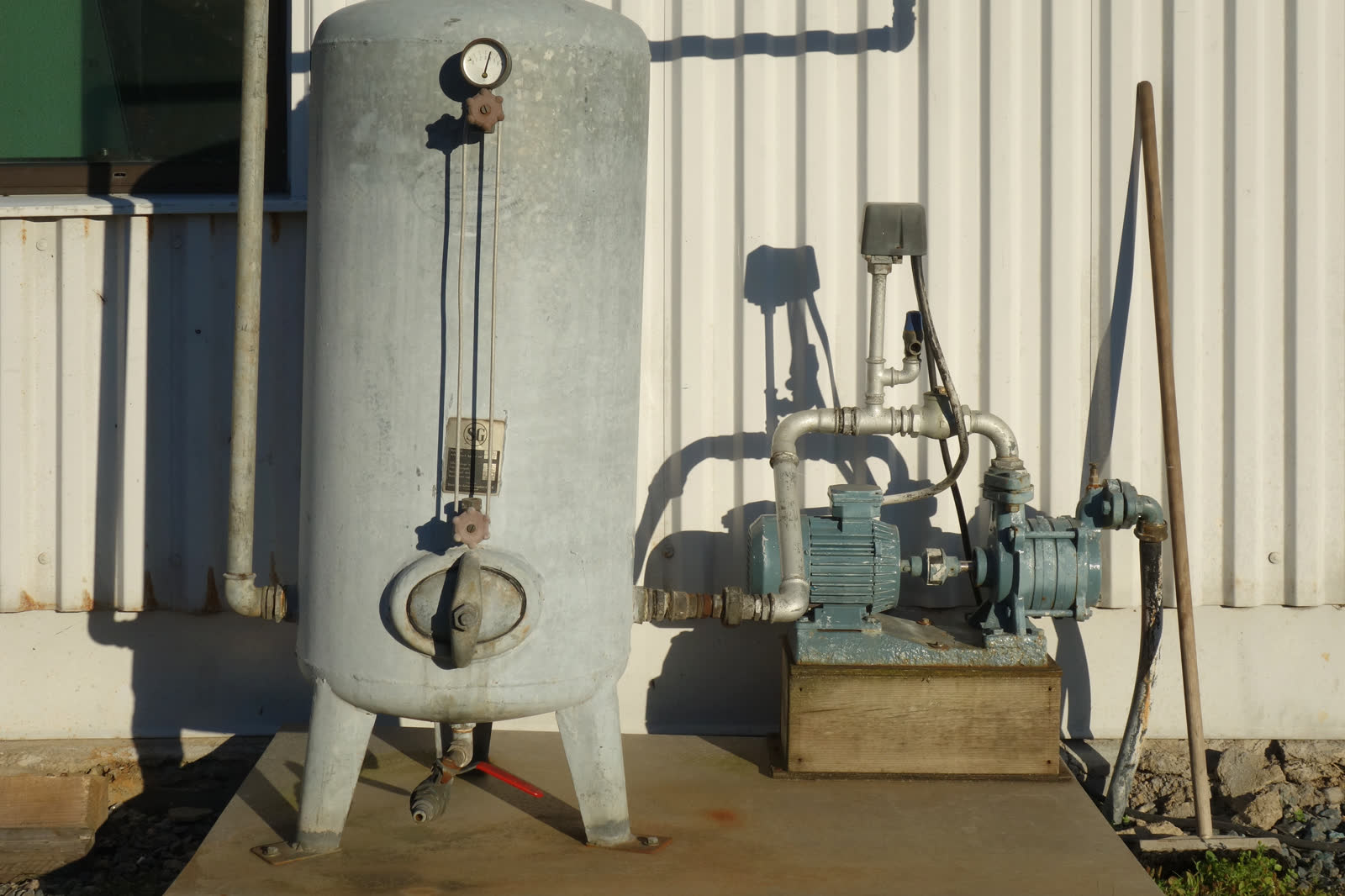Vertical pressure tank connected to a water pump outdoors