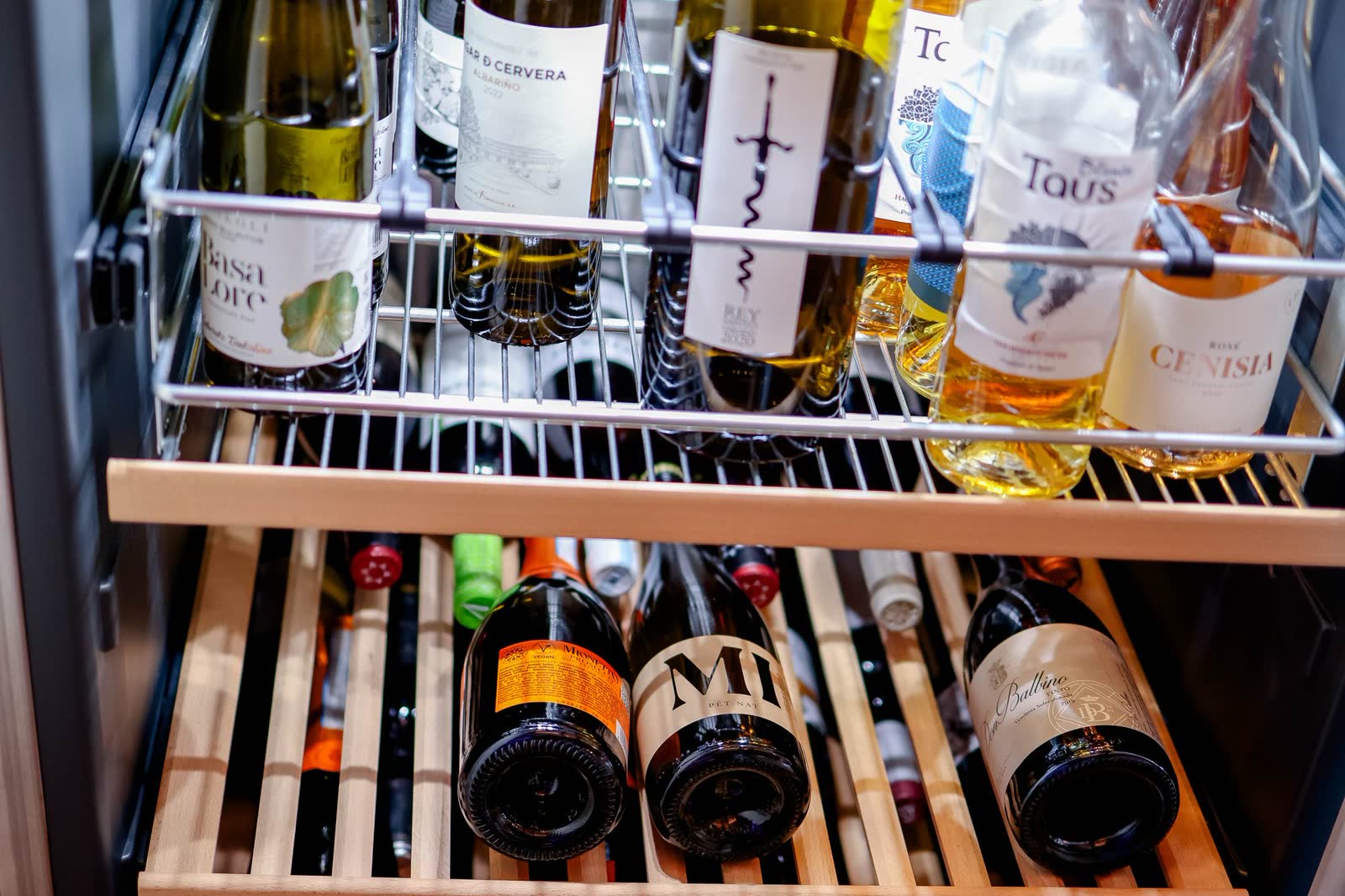 Wine bottles resting on slide-out racks inside a wine cooler