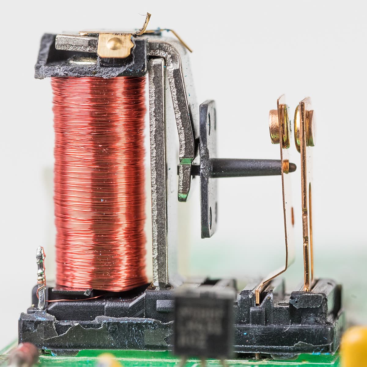 Small PCB relay with its cover removed, showing the coil and switching contacts