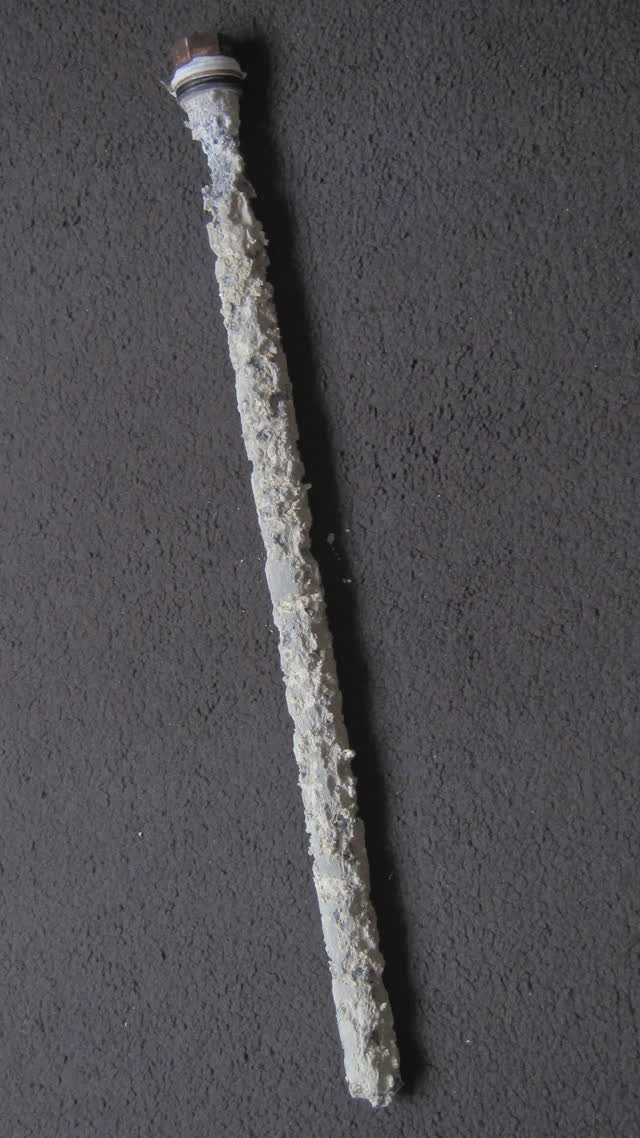 Depleted magnesium anode rod pulled from a water heater tank, eaten down to the core wire