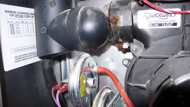 Furnace condensate trap leaking at its rusted screw beside the draft inducer, with the pressure switches below