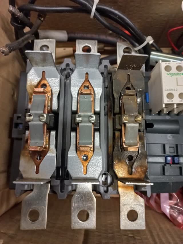 Three-pole contactor opened to show burned, pitted contacts