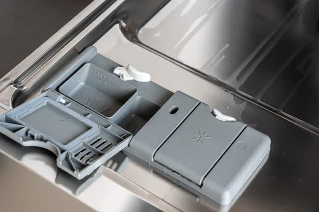Dishwasher detergent and rinse-aid dispenser on the inner door, lid open