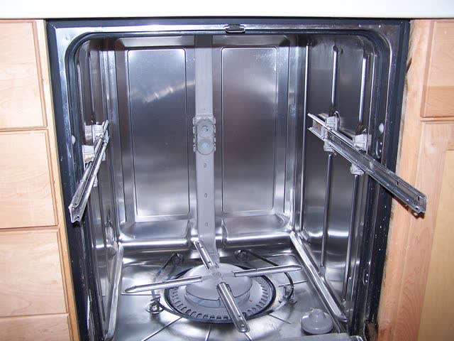 Dishwasher tub with racks removed, showing the lower spray arm and the upper spray feed tube