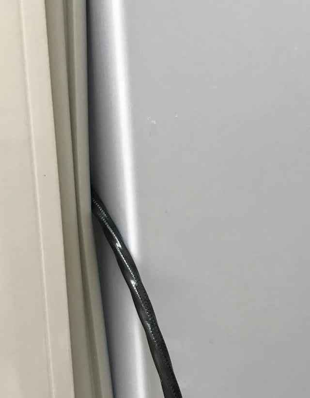 Refrigerator door gasket held open by a cable pinched in the door, leaving a gap where air leaks in