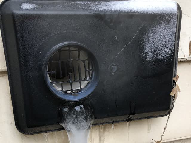 Exterior dryer vent hood in a hard freeze: frost on the hood and an ice buildup at the outlet from condensing exhaust moisture, which can restrict airflow