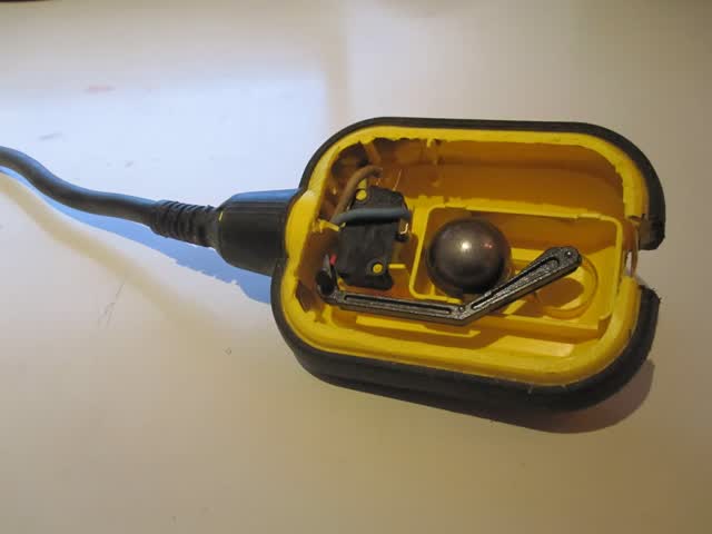 Cable float switch opened to show the steel ball and microswitch that switch the circuit when the float tilts