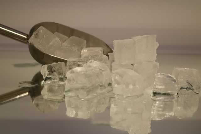 Clear ice cubes with a metal ice scoop