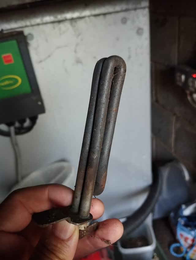 Electric hot-surface igniter element removed from a pellet boiler, held by hand