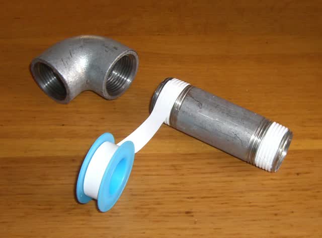 PTFE thread seal tape being wrapped onto the male threads of a pipe nipple before it goes into a fitting