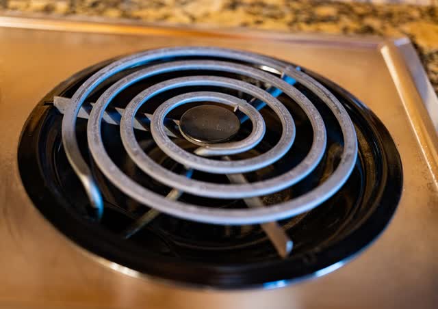 Coil-type electric range surface element seated over its drip bowl