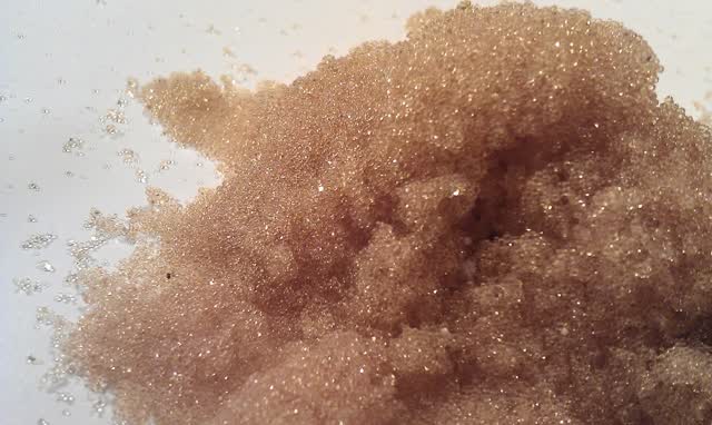Close-up of ion-exchange resin beads, the tiny amber beads inside a softener tank that trade sodium for hardness minerals