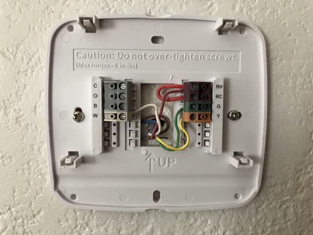 HVAC thermostat sub-base on the wall with low-voltage wires on the R, C, W, Y and G terminals