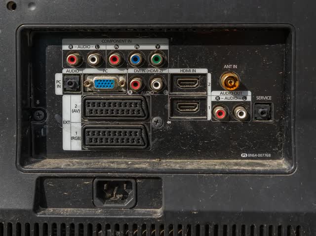Rear input panel of an older LCD TV with two HDMI inputs, component, PC and antenna jacks, audio out and the power inlet