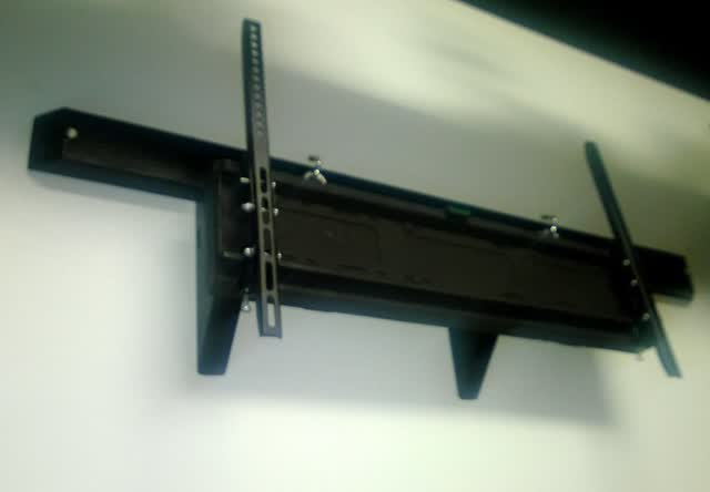 Tilting flat-panel TV wall mount bracket fastened to a wall, with the two vertical arms that bolt to the back of the TV