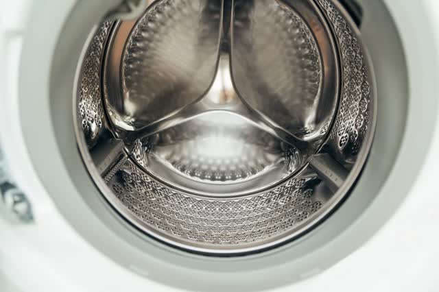 Stainless steel drum of a front-load washer with lifters and the door boot visible